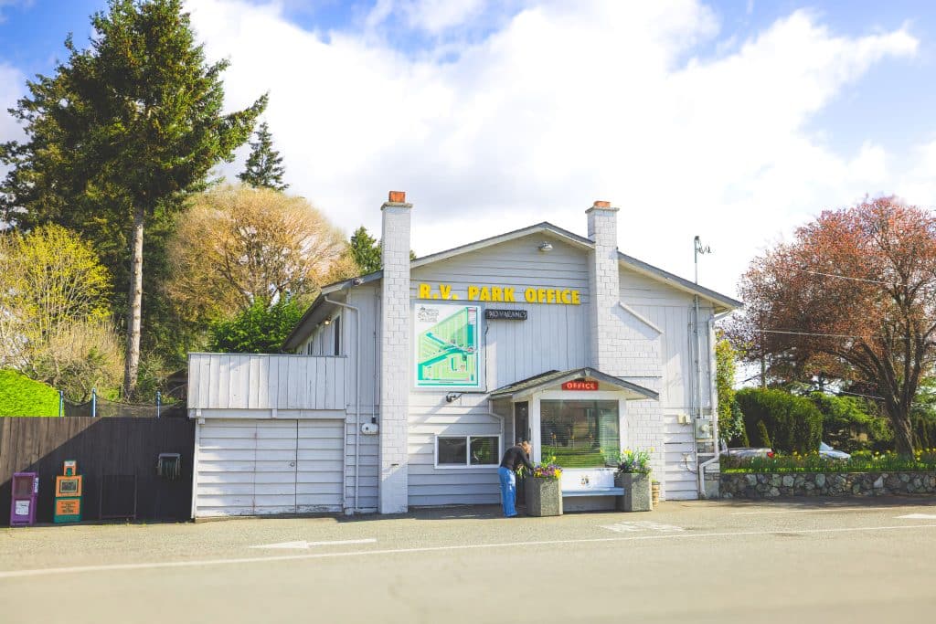White RV park office building at Fort Victoria RV Park with visitor checking in.